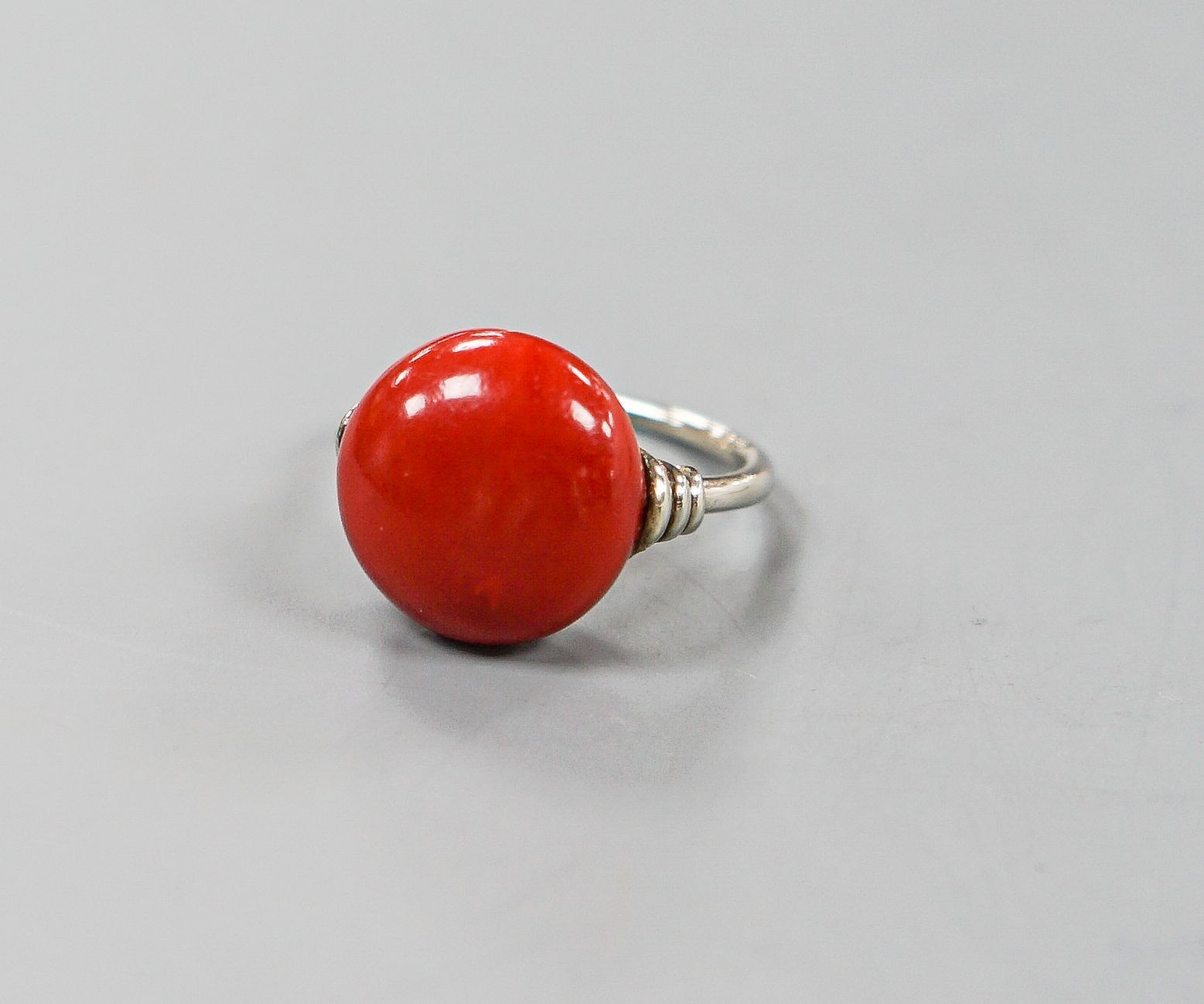 A 585 white metal and stained? cabochon coral set dress ring, size I, gross weight 5.5 grams.